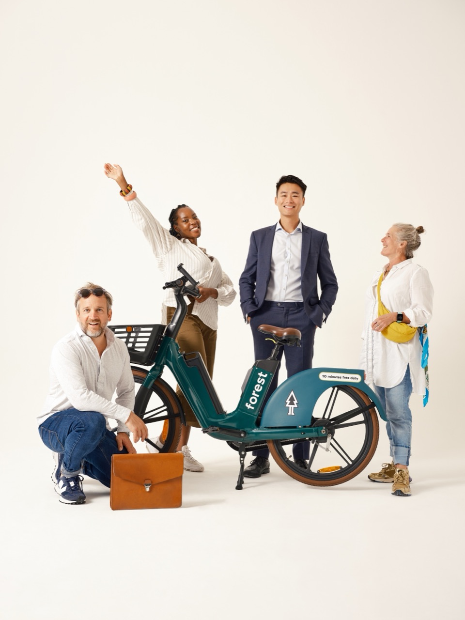 A group of people from different backgrounds standing together with a Forest shared bike.