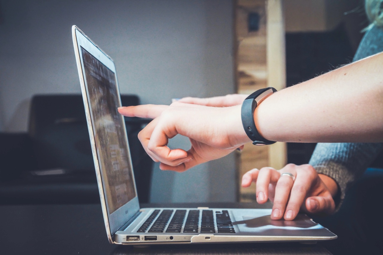 Two people working together at a laptop, one pointing at the screen.