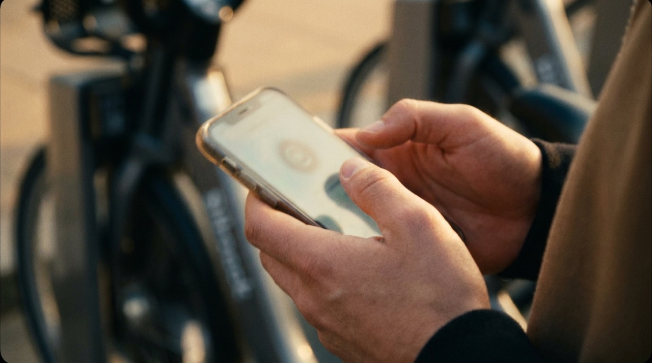 Close-up of hands confirming a payment on a phone beside a shared vehicle.