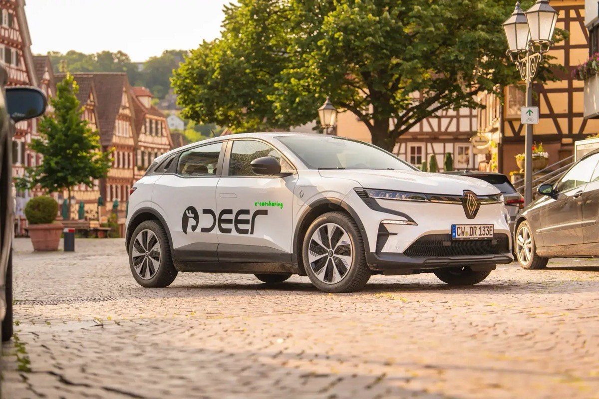 A white deer e-carsharing electric car parked in a German old-town square.